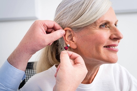 Ältere Frau bekommt Hörgerät angepasst, Hörakustiker berät zum modernen Hörgerät.